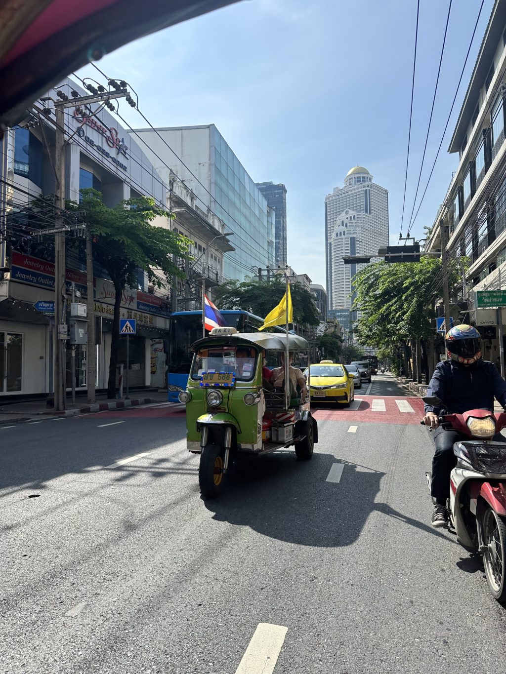 A tuk tuk drives along a busy street in Bangkok during an event.