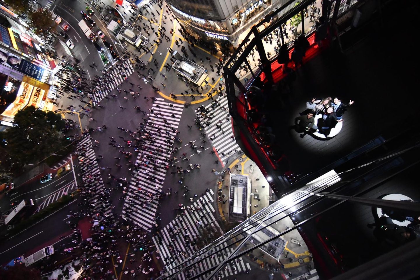 A group stands on a rooftop terrace during an incentive trip over the famous Shibuya Crossing in Toyko, Japan.