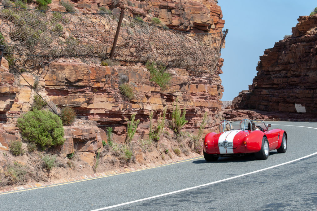A single vintage car drives along Chapman's Peak Drive in South Africa.