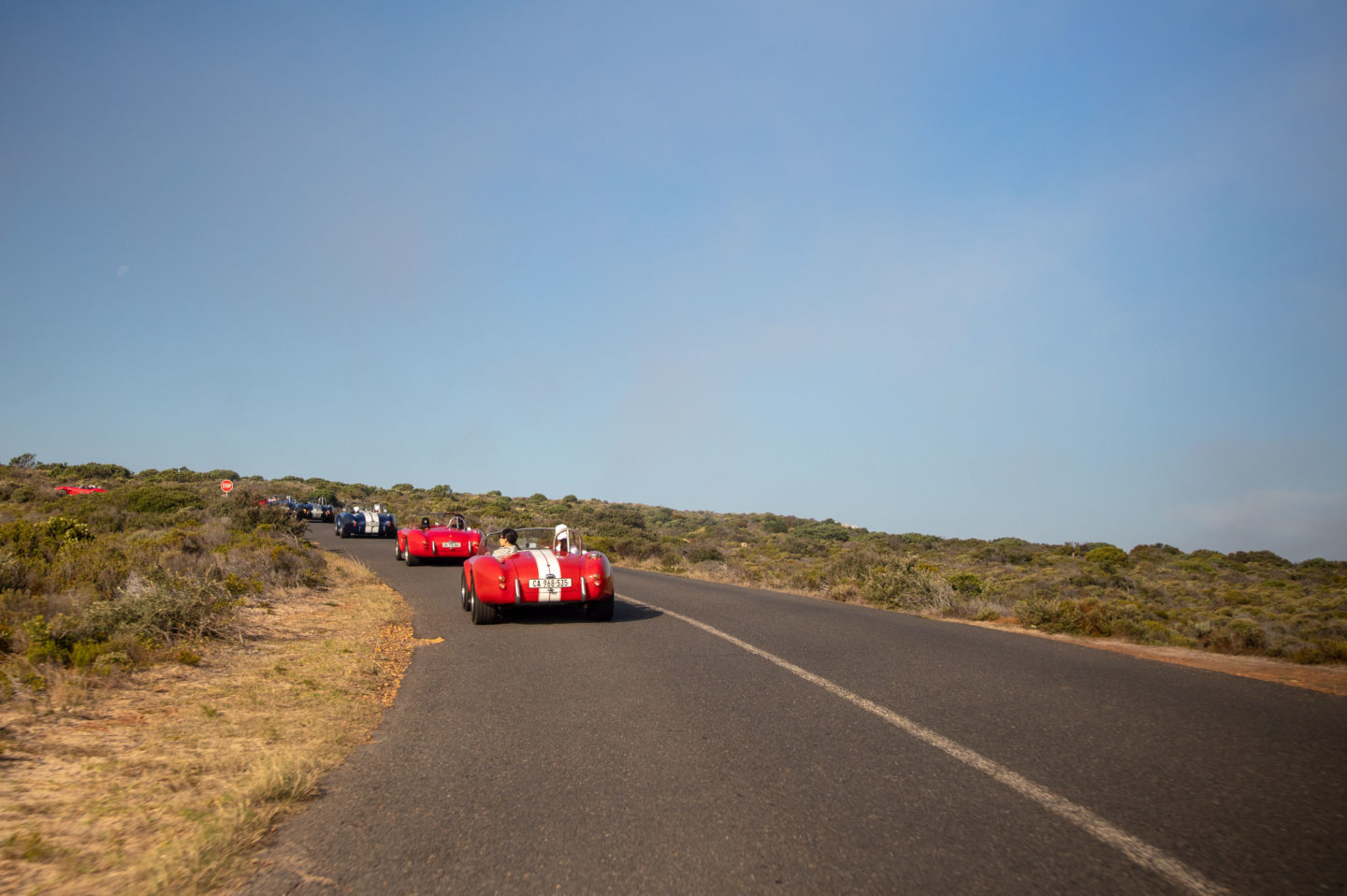 A convoy of vintage cars drives along Chapman's Peak Drive in South Africa.
