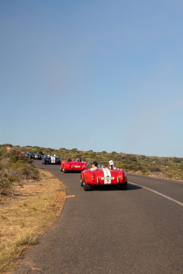 A convoy of vintage cars drives along Chapman's Peak Drive in South Africa.