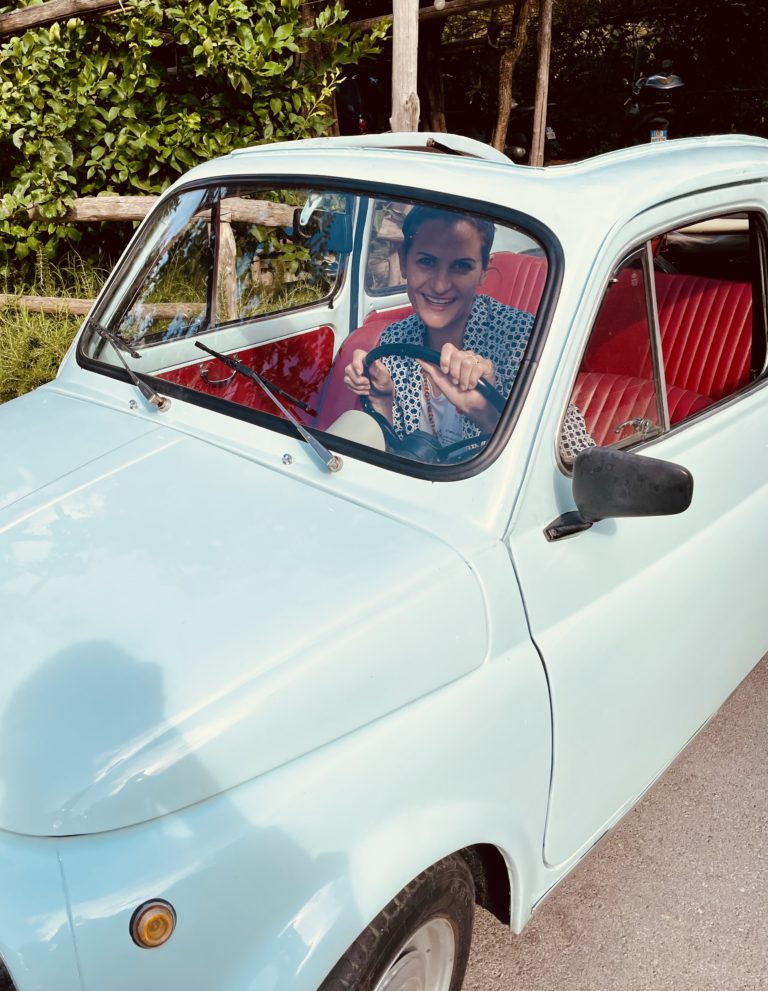 Sabine from the events team sits behind the wheel of a vintage Fiat 500 in Sorrento, Italy.