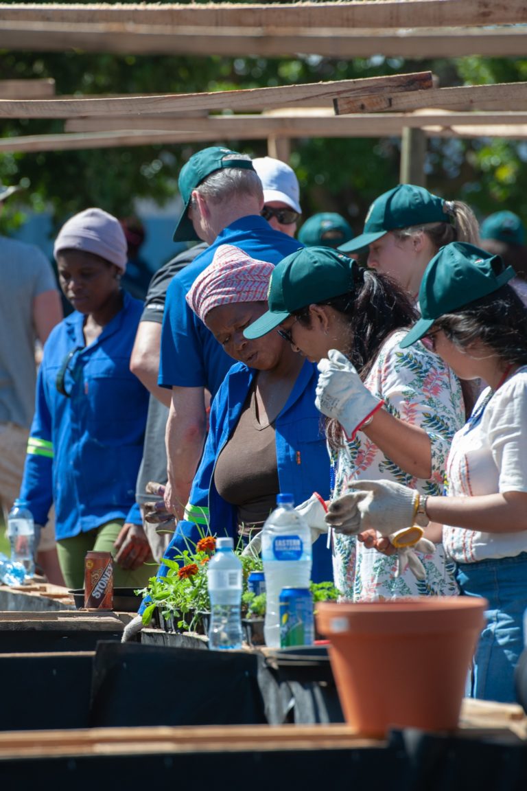 A group of people standing next to each other planting