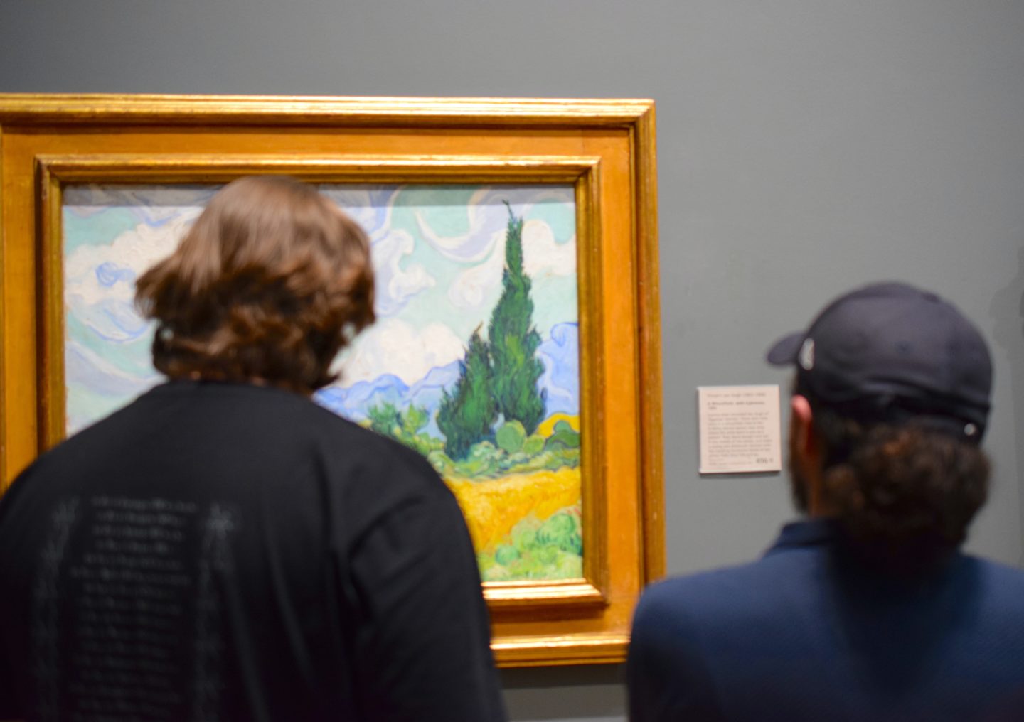 A group of art lovers marvel at a painting by Van Gogh.