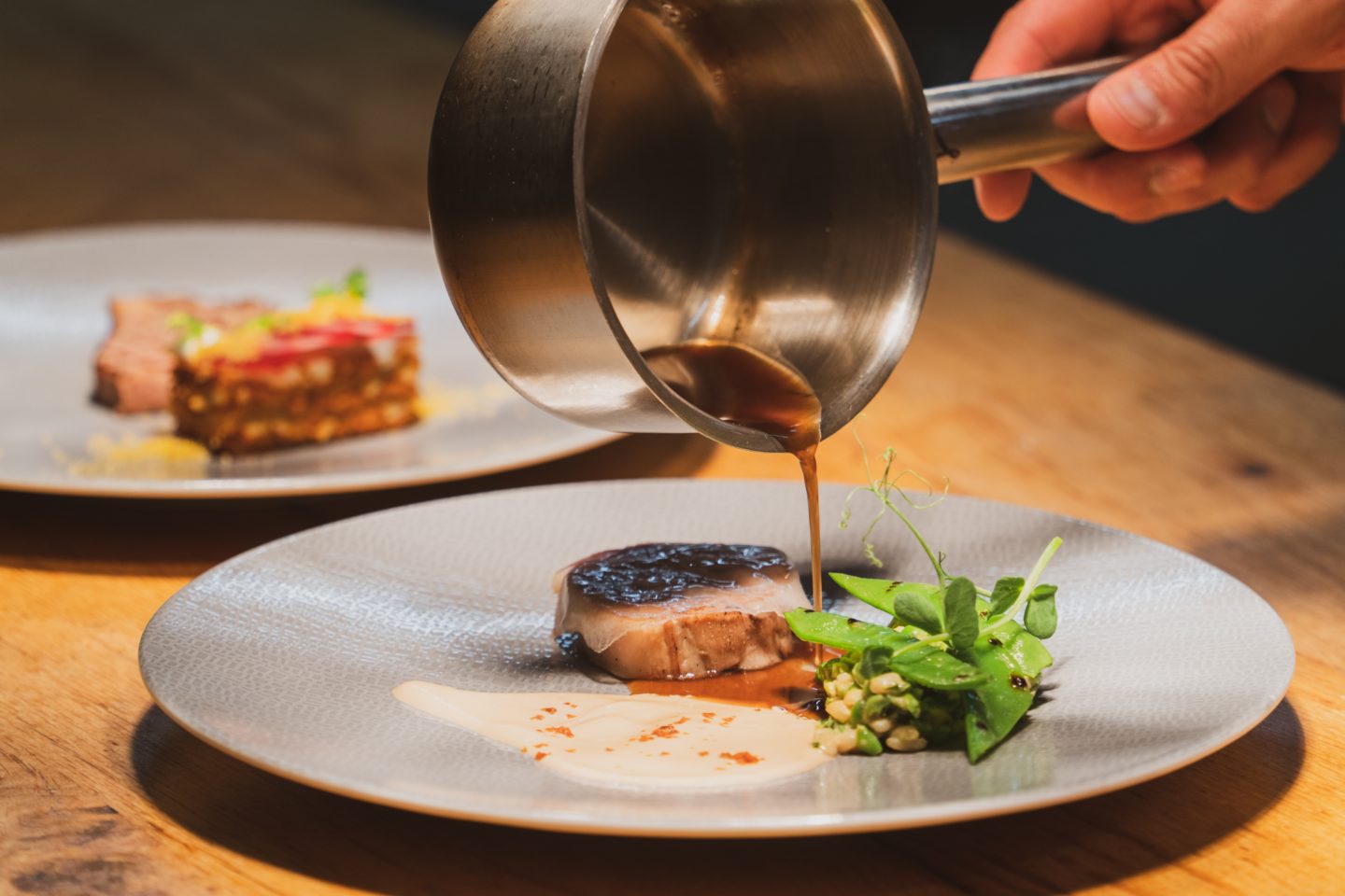 A waiter puts the finishing touches to a dish during a gourmet trip.