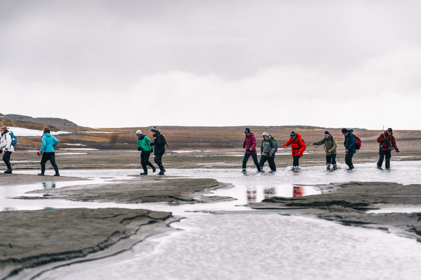 A group treks through the cold water on Spitsbergen.