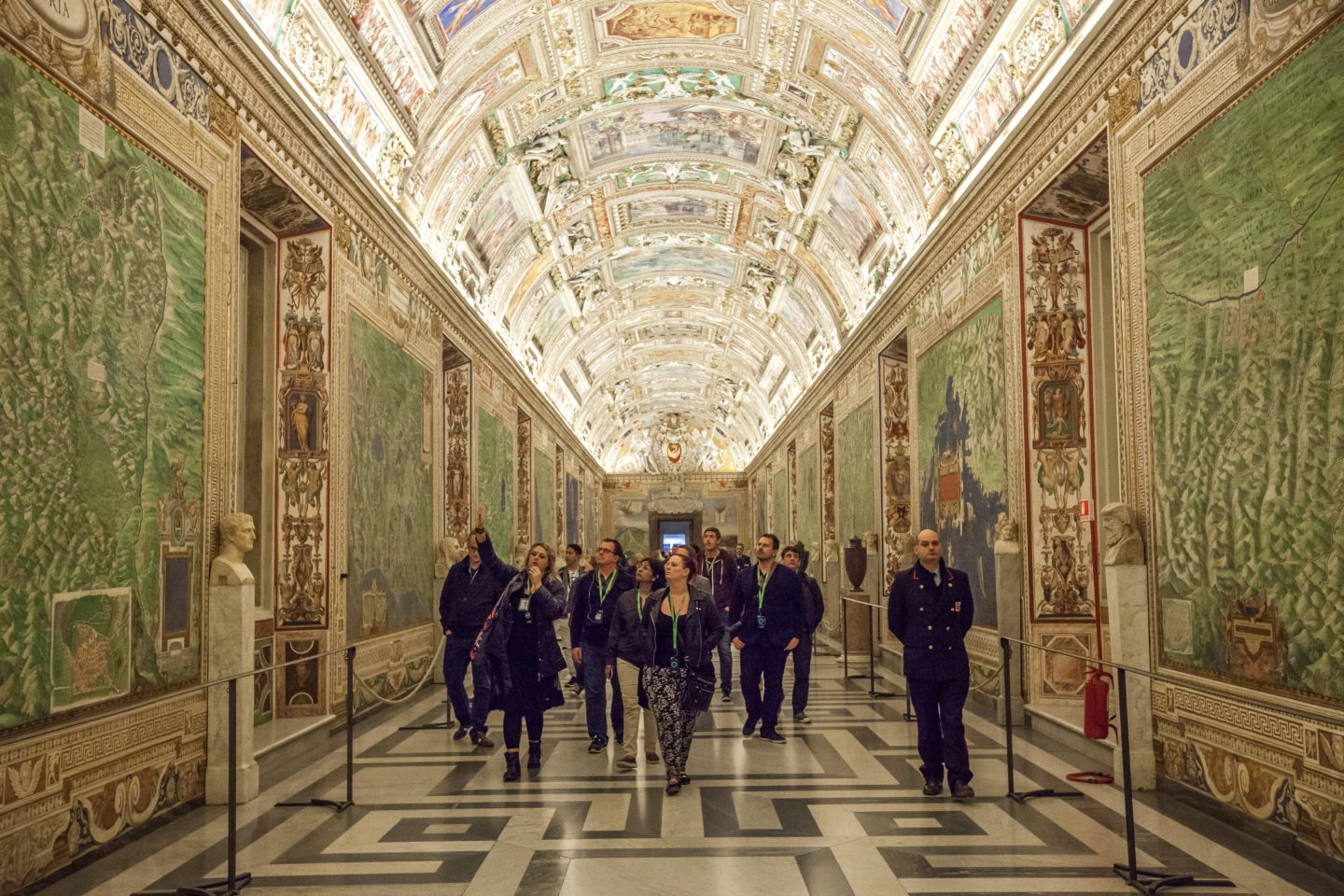 A group is led through the Vatican Museum by a guide.