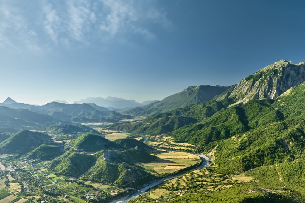 Majestic mountains surround a lush valley, showcasing Albania's stunning natural beauty.
