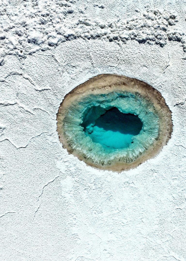 View of a circular lake surrounded by a white salt flat