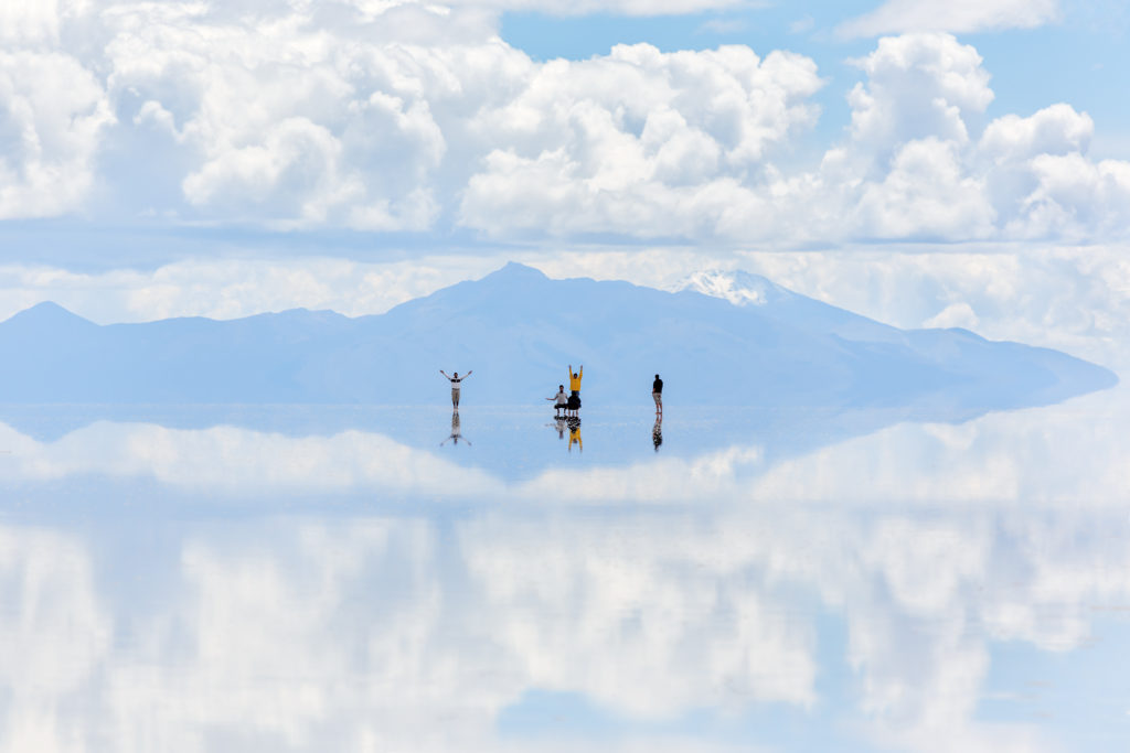 People on the mirror like salt flats of the Salar de Uyuni