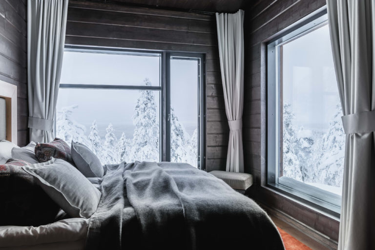 Cozy bedroom with a large window overlooking a snow-covered forest