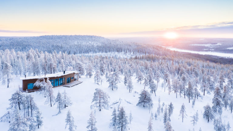 Cabin in a snowy forest, with a beautiful sunrise in the background