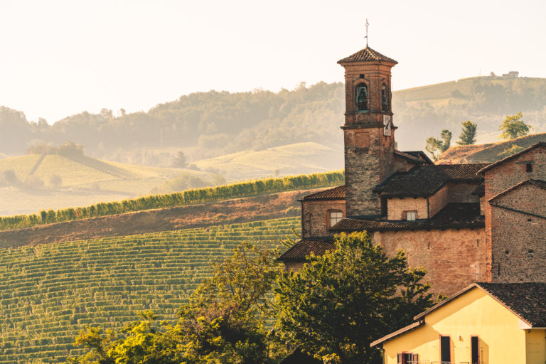 Picturesque view of a church, vineyards, and rolling hills in the Italian countryside