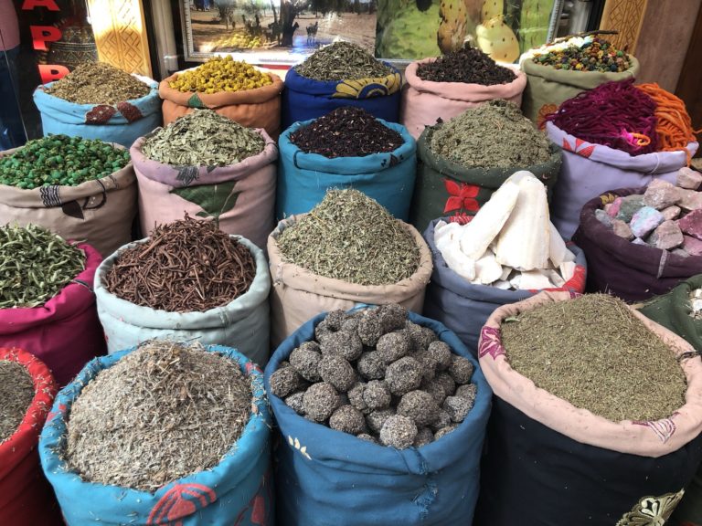 A variety of spices and herbs displayed in colorful sacks at a market stall