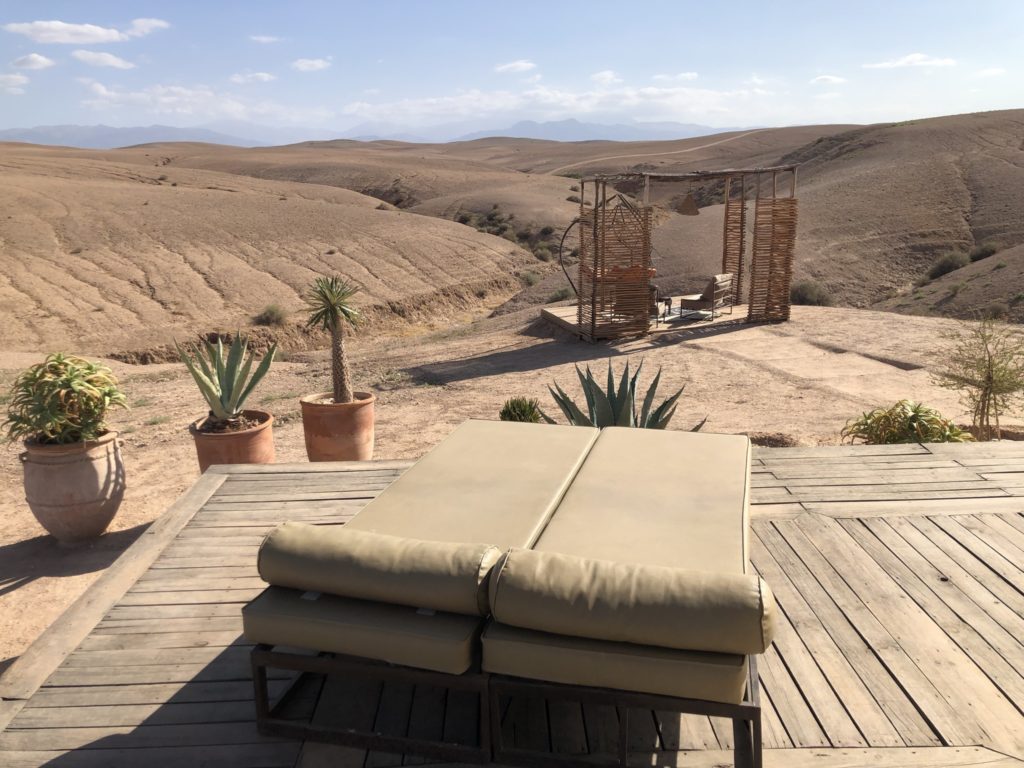 A luxurious tent with a seating area overlooking a stunning desert landscape and mountains