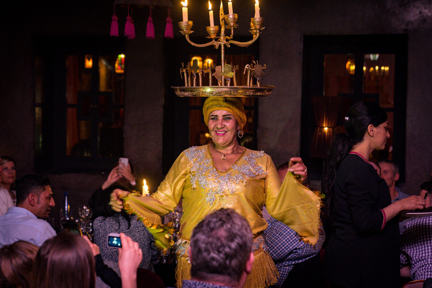 Woman balances a lit candelabrum on head while performing during dinner in Petit Bazar