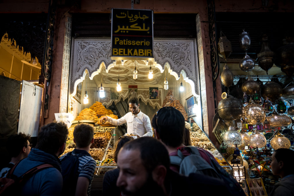 Crowd before a food shop, vibrant sights and smells of Marrakech's colorful souks