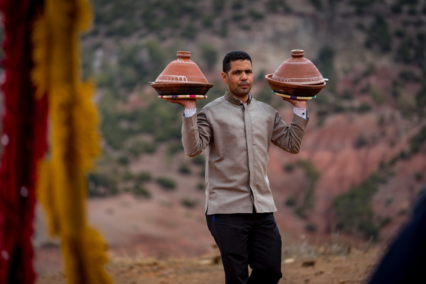 Suited man balances two pots for serving guest