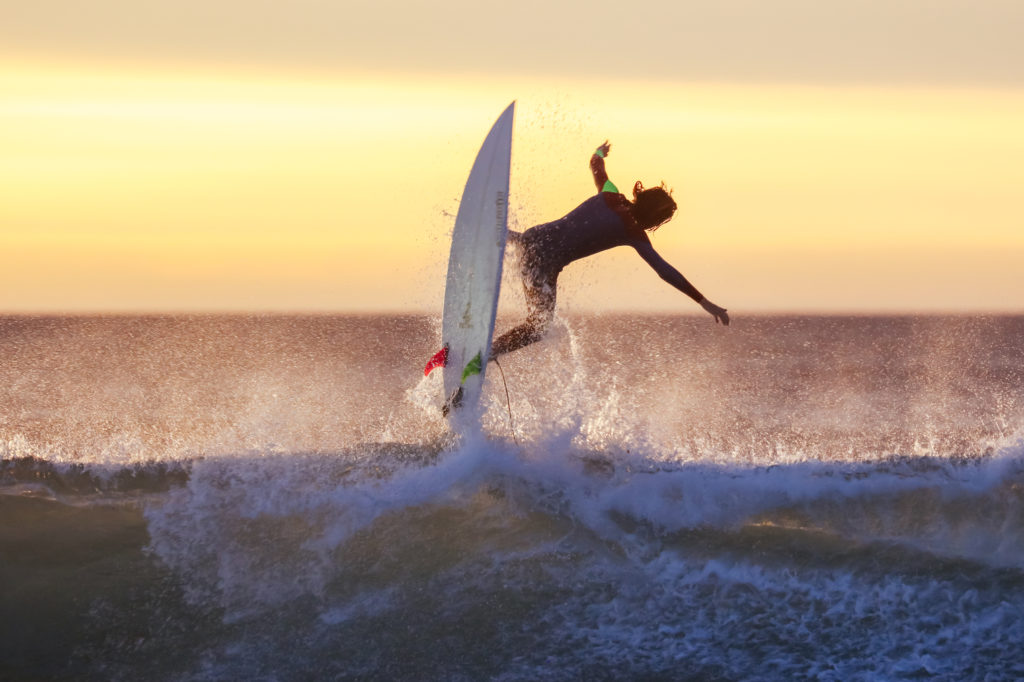 Surfer leaps into air on their board, riding the waves at Bells Beach