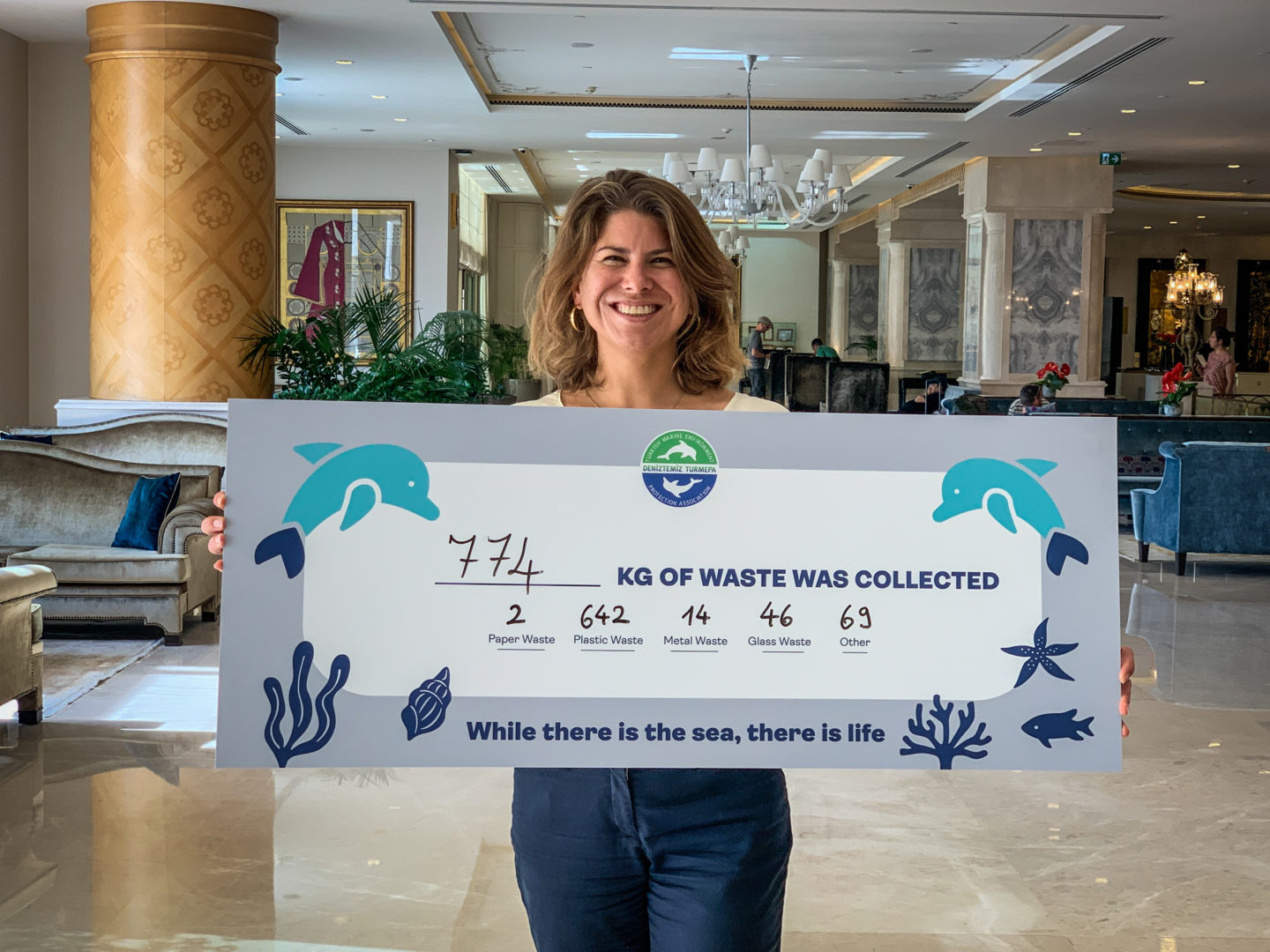 Nina holding a sign up showcasing how much trash was collected