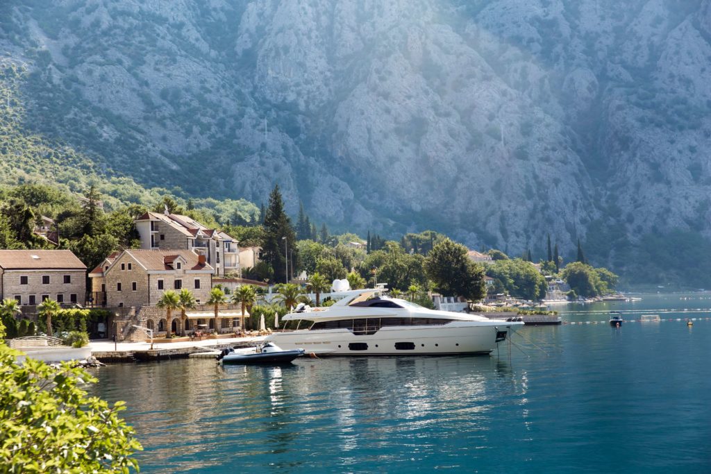 Luxury yacht moored by a stone village on the calm bay in Montenegro.