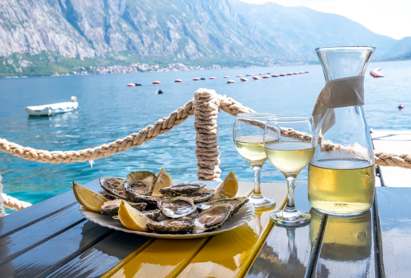 Fresh oysters and white wine by the Bay, Montenegro, with mountain views in the background.
