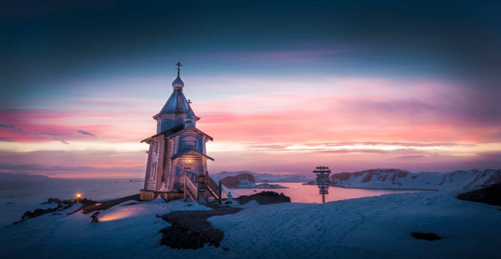 A church stands atop a snowy hill, a serene winter landscape