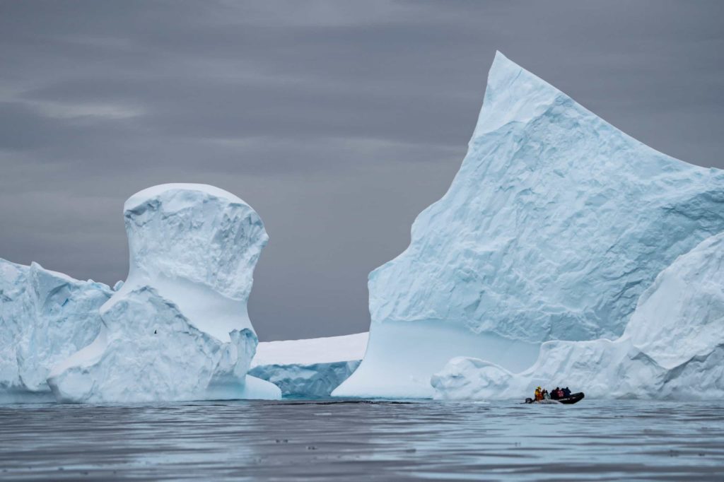 Expedition team aboard a boat close to huge iceberg in Antarctic