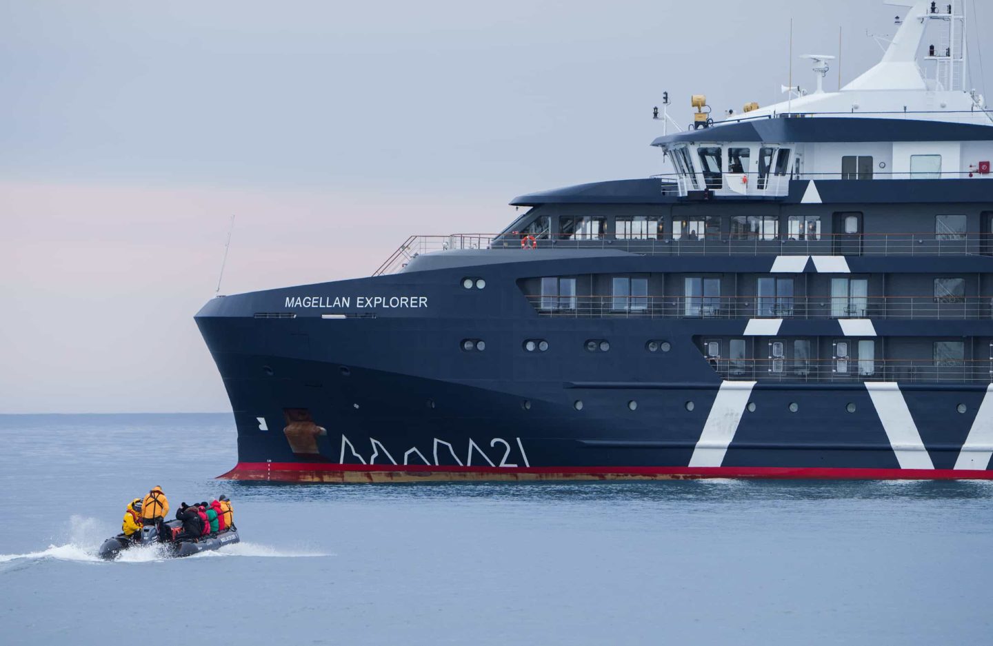 Expedition team navigate a small motor raft towards a cruise ship