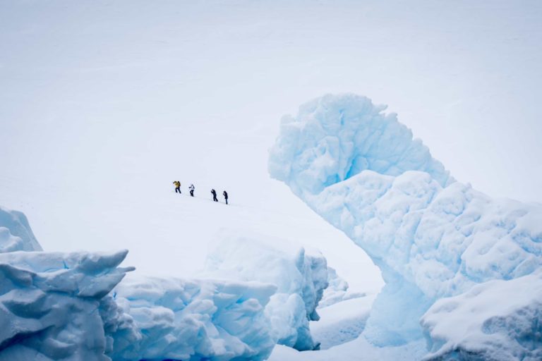 Team of explorers hiking across a snowy Antarctic mountain