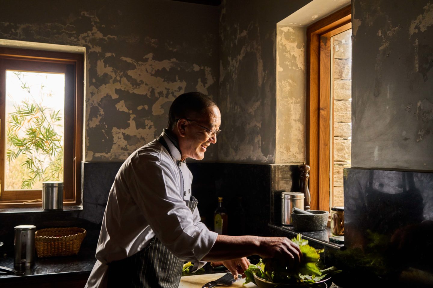 Chef at Prana Lodge happily preparing food in a kitchen illuminated by natural light