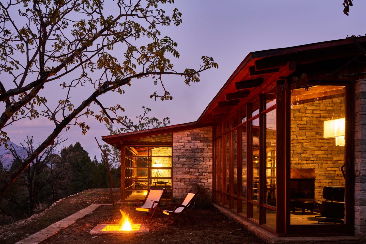 Cozy evening at Prana Lodge in Kumaon, with a fire pit glowing as dusk settles