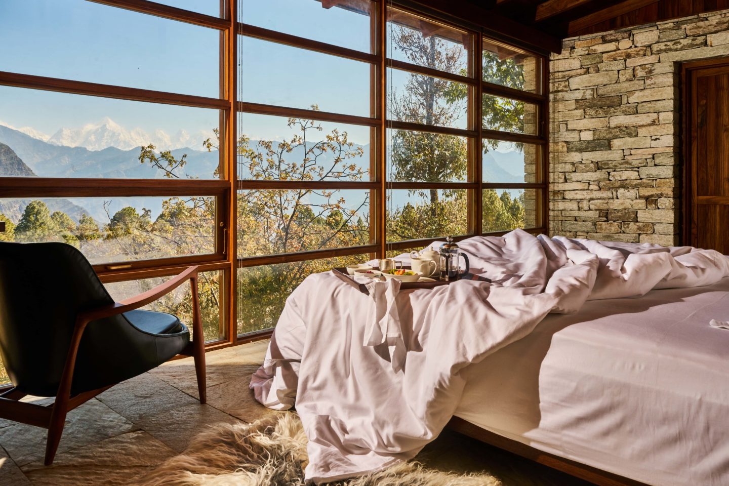 Cozy bedroom with a large window offering a breathtaking view of the snow-capped Himalayas