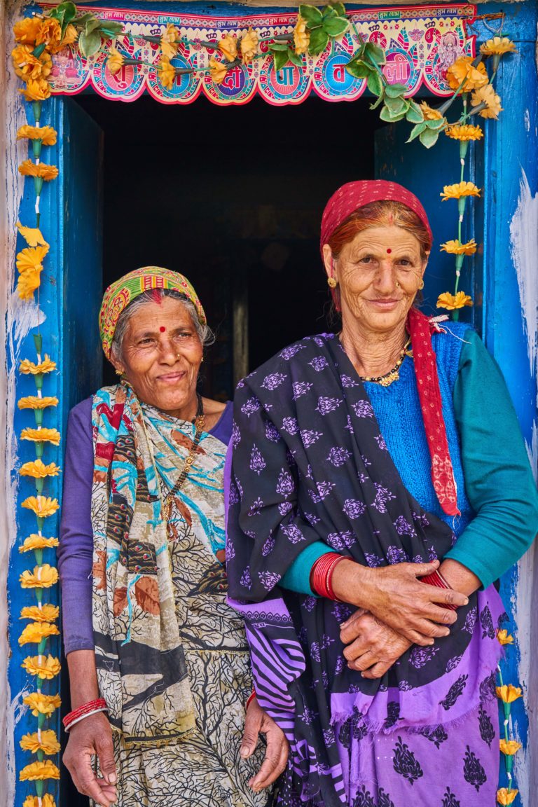 Two women in traditional Indian attire from a mountain village, standing in a decorative doorway