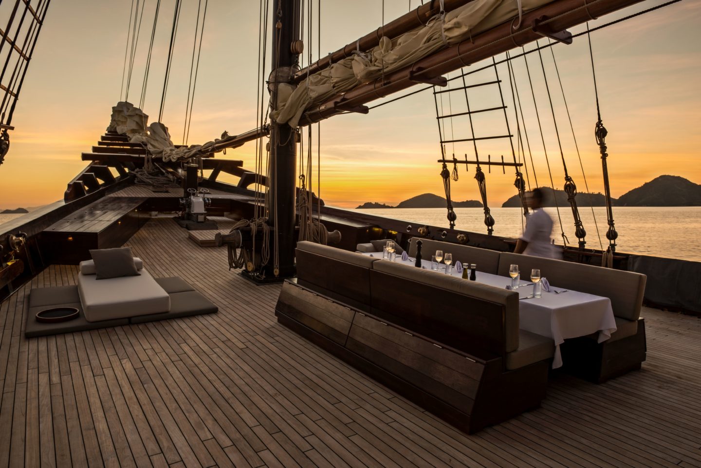 Sunset view of a dining room on a sailing ship, with cozy seating and serene atmosphere