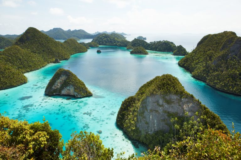 Scenic view of vibrant greenery covered on Island rocks and clear blue waters, part of the Raja Ampat in Indonesia