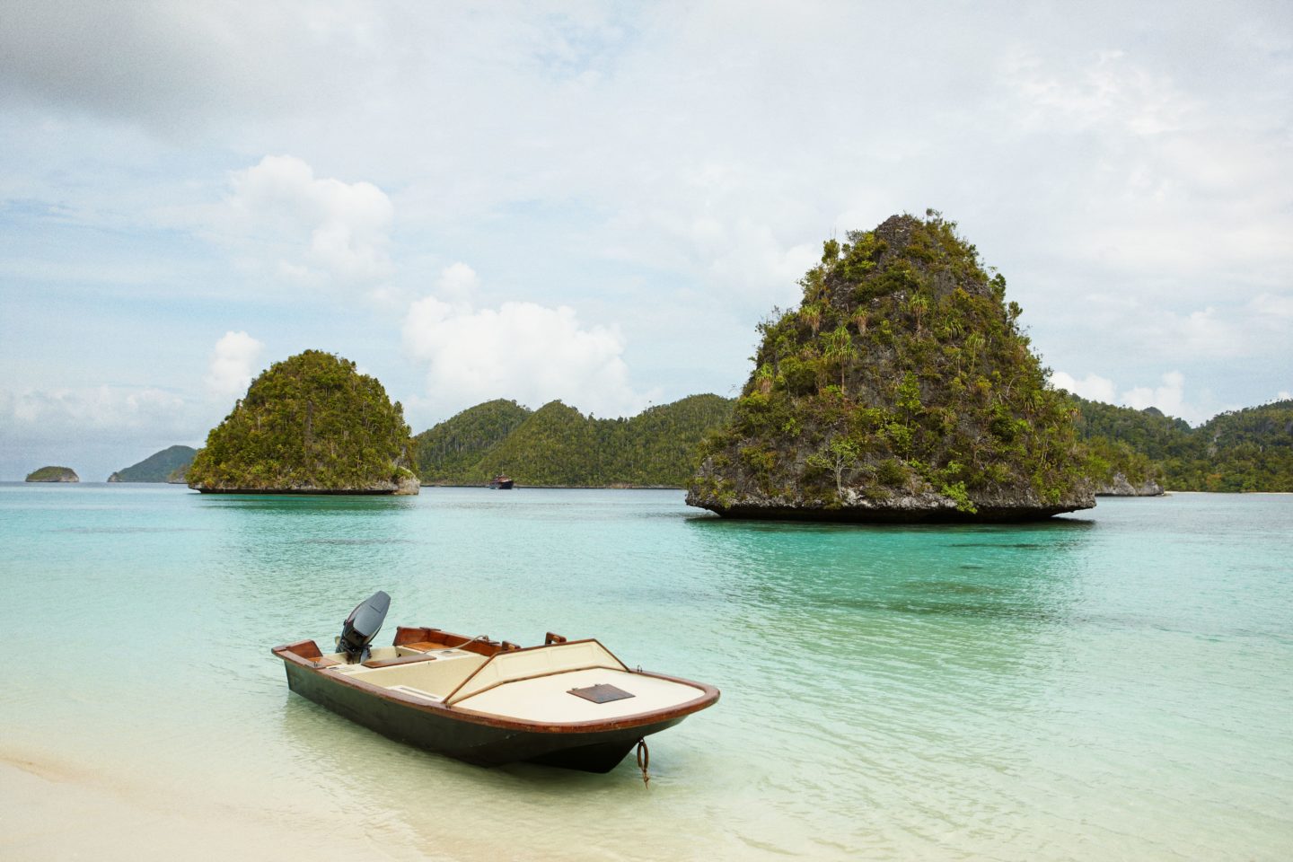Small boat awaits on the beach, inviting to explore Raja Ampat's stunning waters
