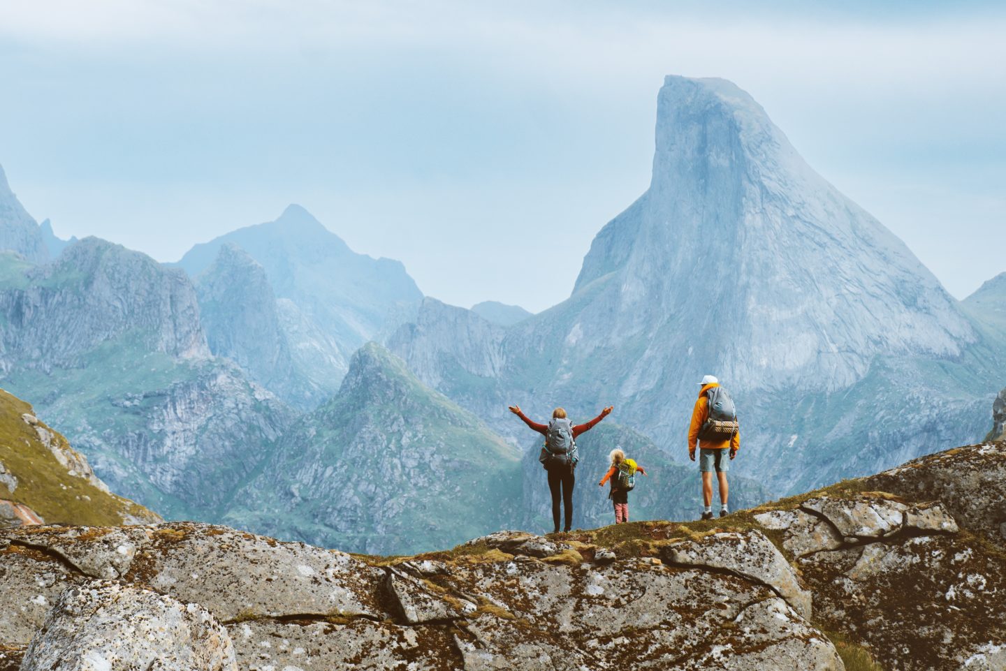 Family with a child hiking on a rocky mountain ridge in the Lofoten Islands, Norway