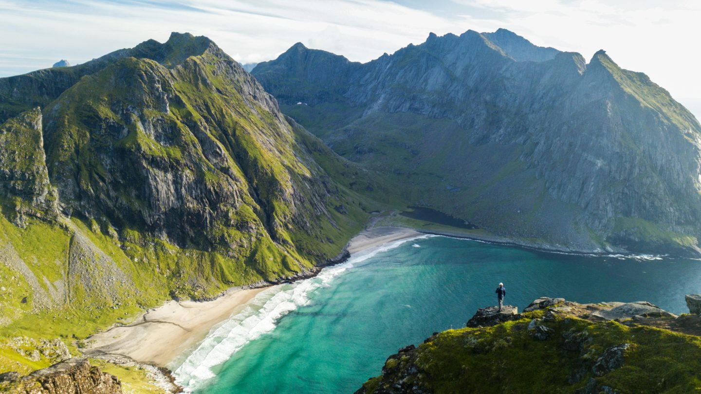 Scenic coastal landscape on Moskenesøya, where a person stand on a cliff edge