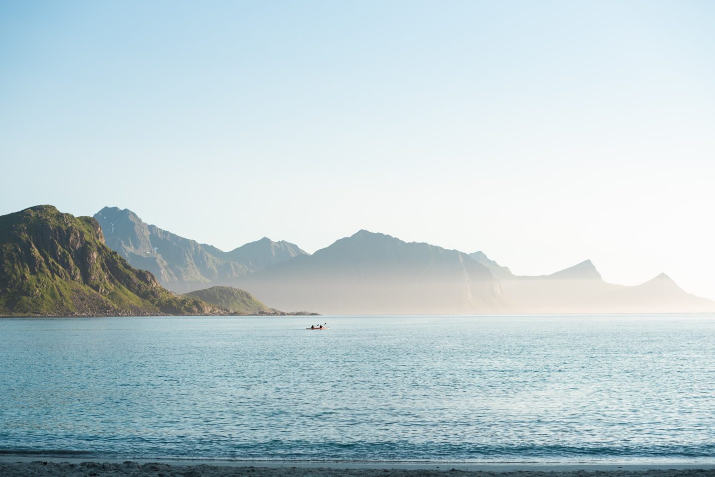 Scenic view of a fjord in Norway with a small boat on the water and rugged mountains on the horizon