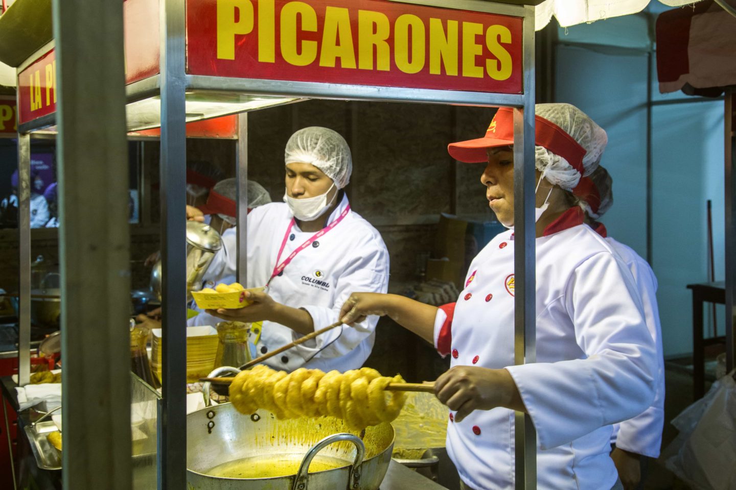 Chefs preparing traditional Peruvian street food at a lively food stall