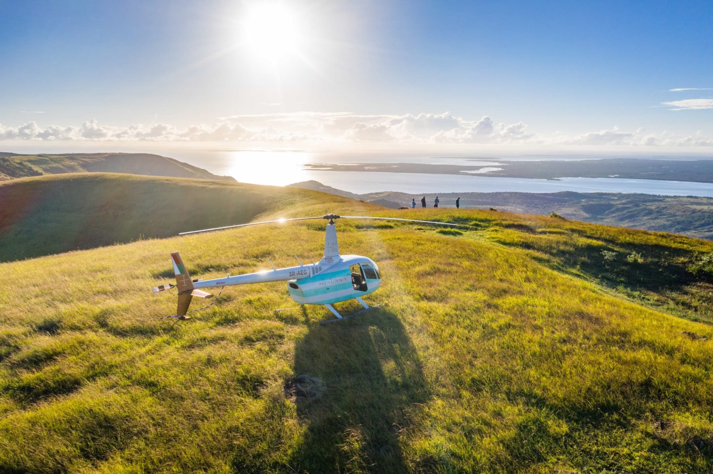 Helicopter on a hilltop, with a scenic view of Miavana in the background