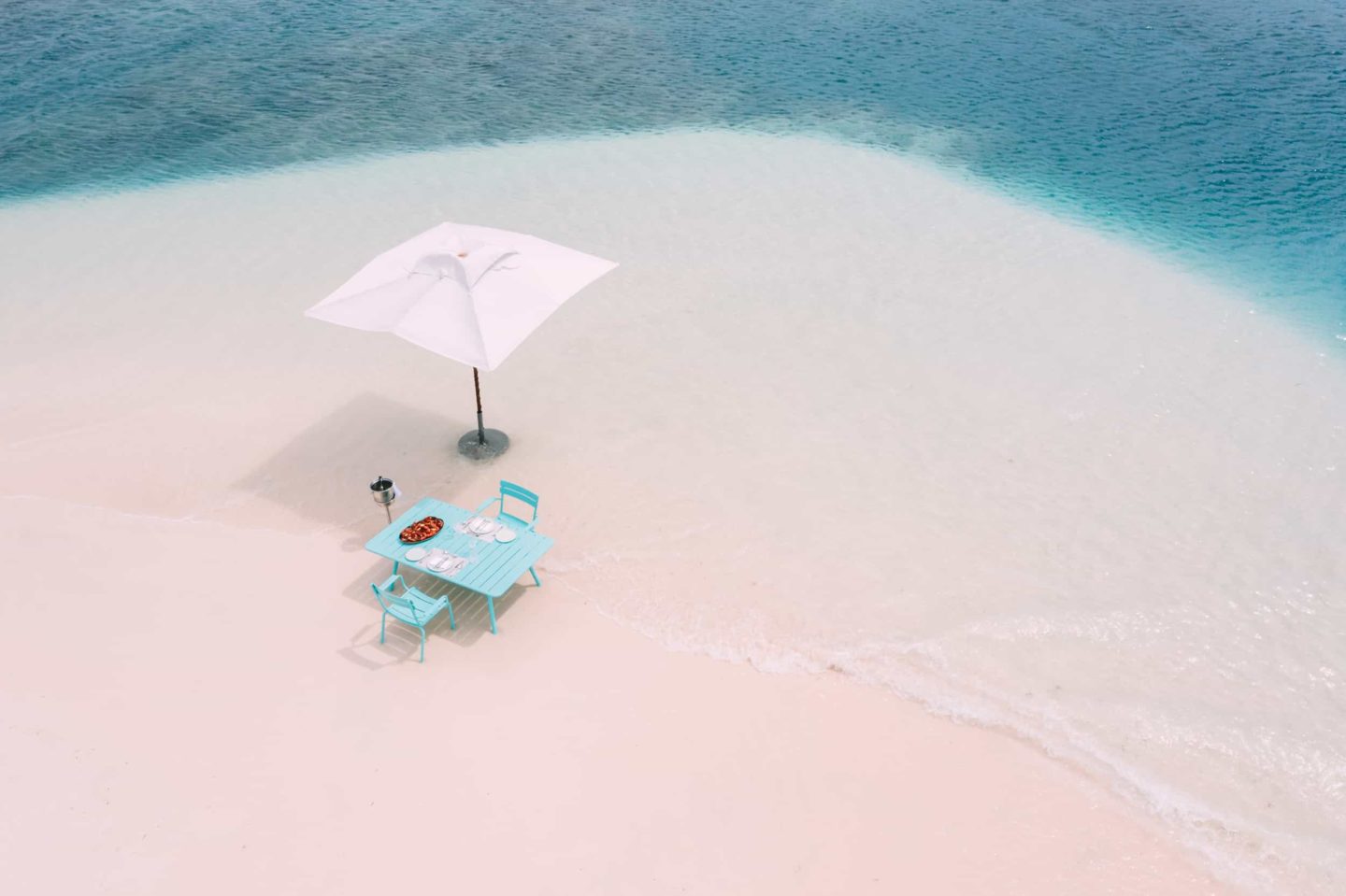 Beach with a table and umbrella set up for lunch at Miavana