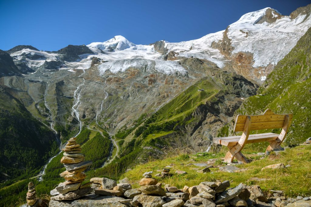 Bench positioned on a hill, with stunning views of glaciers in Saas Fee's picturesque terrain