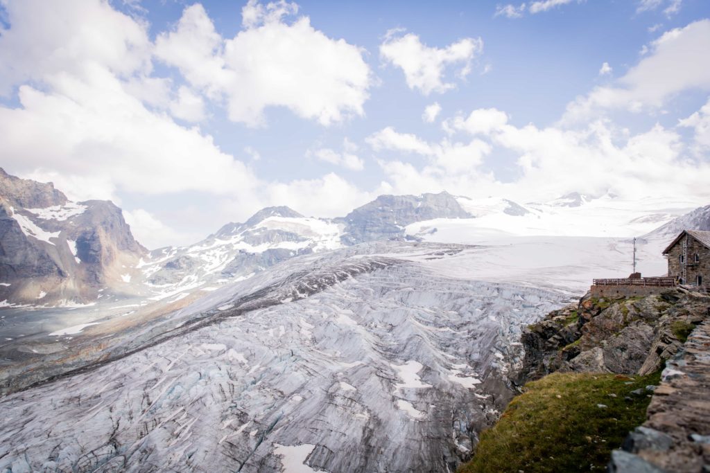 Mountain with a house perched on top, overlooking a glacier in Saas Fee